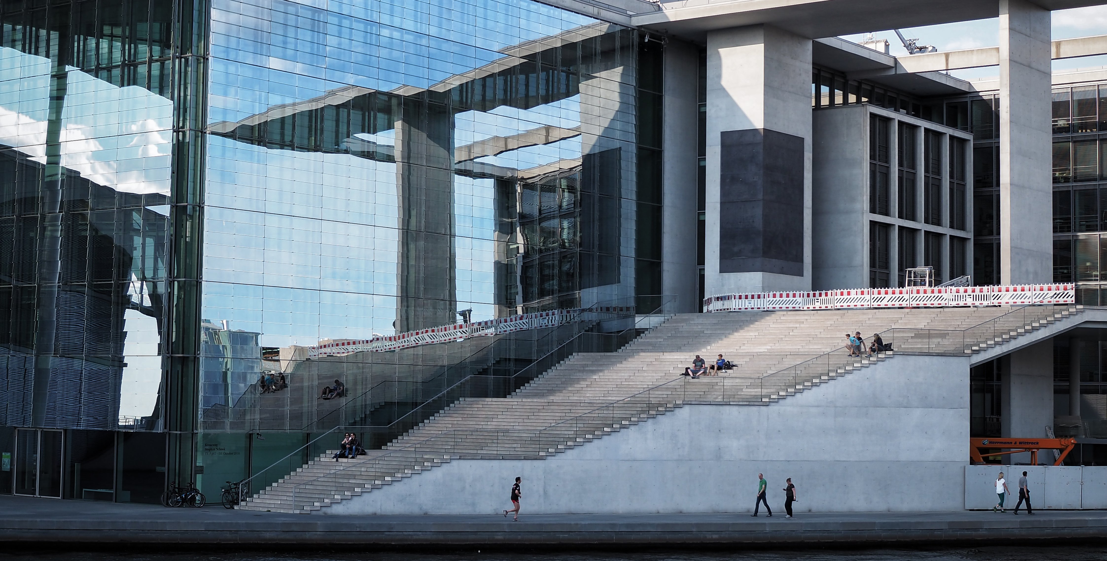 Das Foto zeigt einen Teil eines Geb&auml;udes im Regierungsviertel. Zu sehen ist eine gl&auml;serne Fassade und eine hohe Treppe.